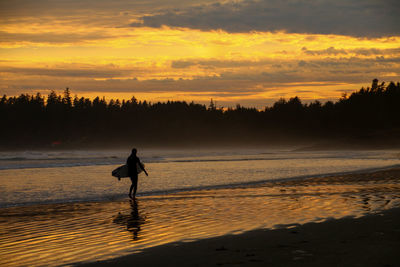 Silhouette of a surfer on beach at sunset
