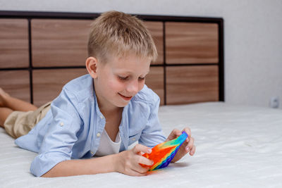 Boy playing with toy on bed at home