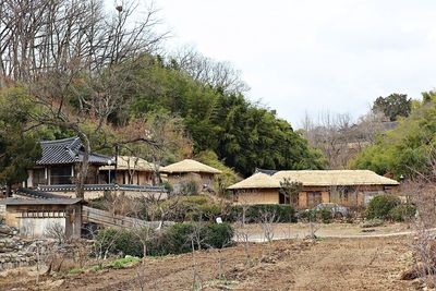 House amidst trees and houses against sky