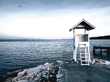 Lighthouse by sea against sky