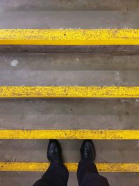 Low section of man standing on yellow road