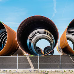 Low angle view of industrial tubes against sky