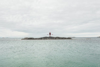 Scenic view of kayaker on rock on sea