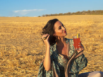 Portrait of young woman drinking water in field