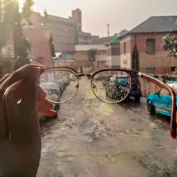 Close-up of sunglasses on glass against building in city