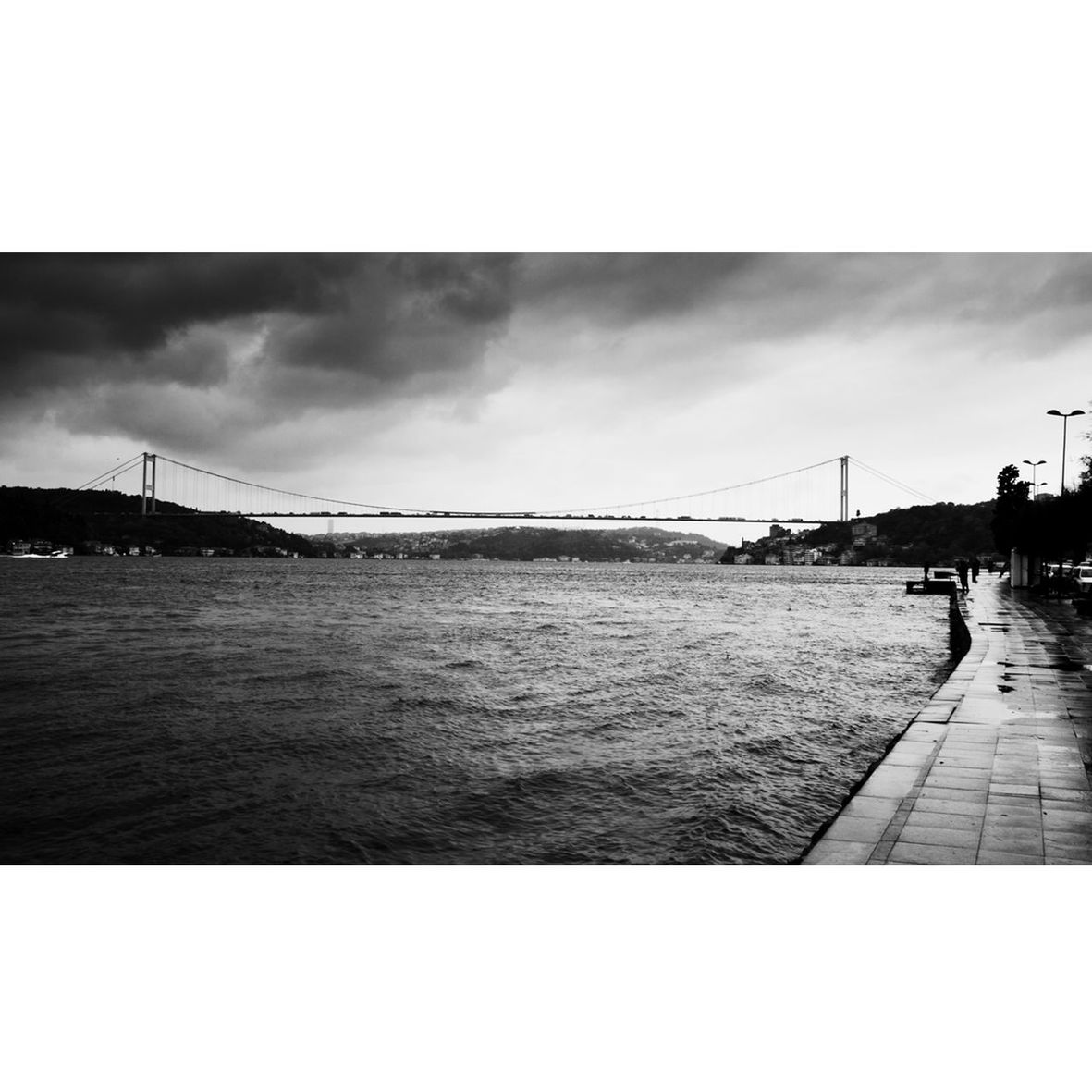 sky, water, built structure, architecture, transfer print, cloud - sky, building exterior, auto post production filter, cloudy, river, men, cloud, incidental people, connection, mid distance, city, bridge - man made structure, sea, day