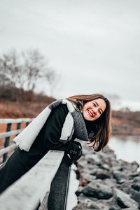 Portrait of smiling young woman against snow during winter