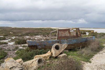 Abandoned boat on field against sky