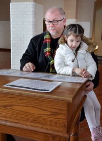 Grandfather and granddaughter reading paper at table