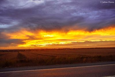 Scenic view of road against dramatic sky during sunset