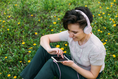 Young woman using mobile phone while standing by plants