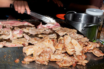 Person preparing meat on barbecue grill