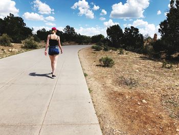 Rear view of woman on road against sky