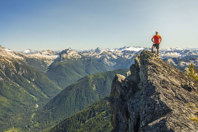 Climber stands on the summit of a rocky mountain peak, b.c. canada