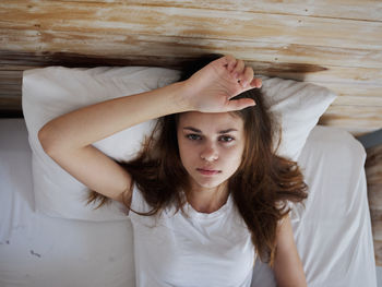 Portrait of young woman lying down on bed