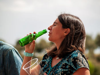 Man and woman drinking beer against sky