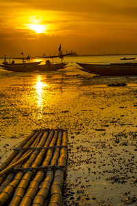 View of the beach with some boats and bamboo wharf during sunset in bangkalan, madura, indonesia