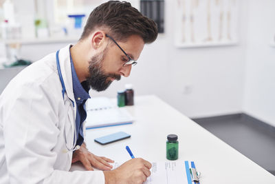 Scientist writing prescription at desk in clinic