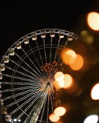 Low angle view of illuminated ferris wheel against sky at night