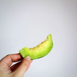 Cropped image of hand holding fruit over white background
