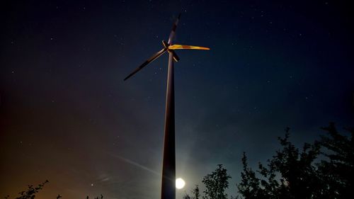 Low angle view of wind turbines against sky at night