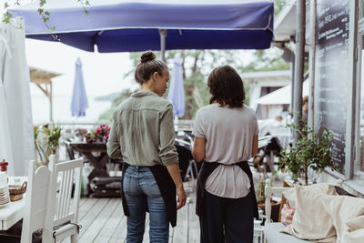 Rear view of businesswoman with coworker standing in restaurant