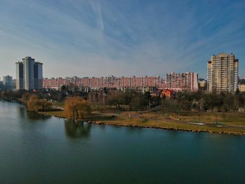 Buildings by river against sky in city