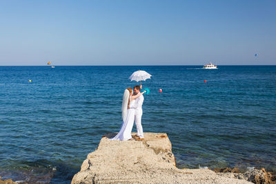 Woman standing by sea against clear sky
