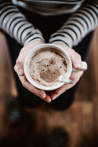 Low section of woman holding hot chocolate at home