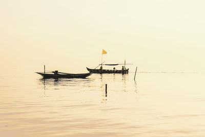 Silhouette person fishing in sea against sky during sunset