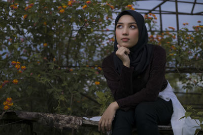 Thoughtful young woman sitting by flowers