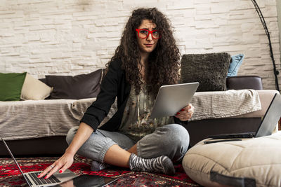 Young woman using laptop while sitting on sofa at home