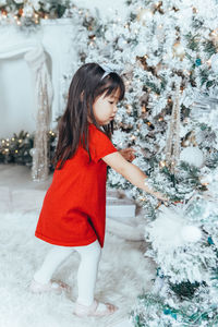 Cute girl touching christmas tree at home