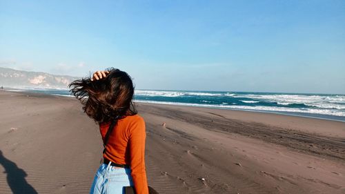 Woman standing on beach against blue sea and blue sky