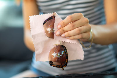 Midsection of woman cleaning sunglasses