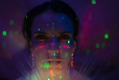 Portrait of beautiful young woman against illuminated background