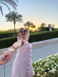 Young woman wearing sunglasses standing against plants