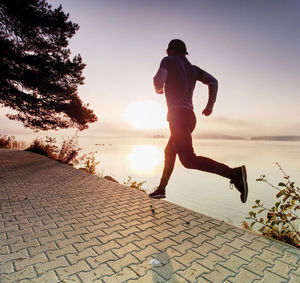 Full length of man running on footpath against sky
