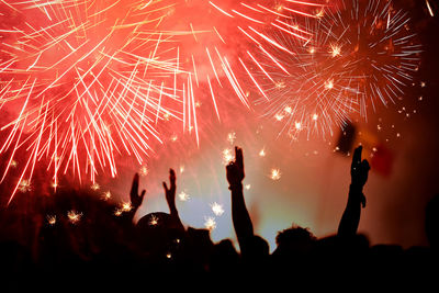 Silhouette people enjoying firework display at night