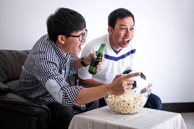 Friends cheering while watching sports on tv at home