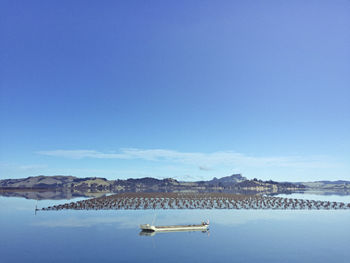 High angle view of fishing boat moored on calm lake against blue sky