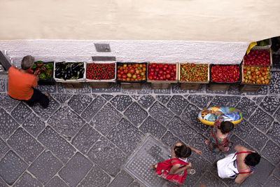 High angle view of vendor with vegetables by people on street at market