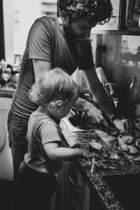 Baby boy looking at father preparing food at home