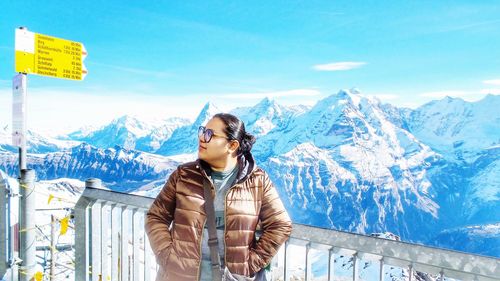 Woman standing on snowcapped mountain against sky