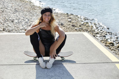 Woman sitting on skateboard at road