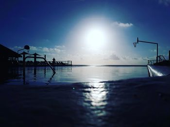 Silhouette people swimming in pool against sea during sunset