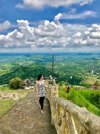 Rear view of woman standing on landscape against sky