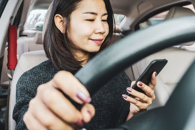 Midsection of woman using mobile phone in car