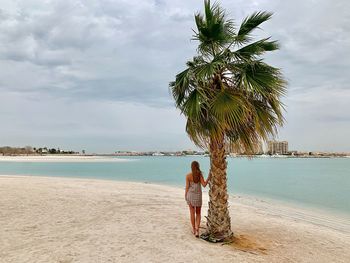 Woman standing on beach against sky