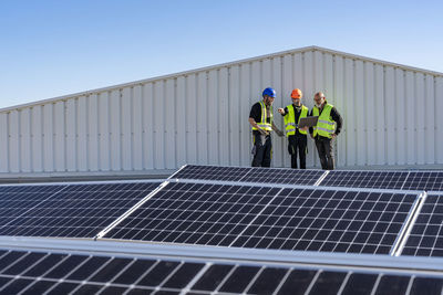 Technicians with laptop discussing on solar panels